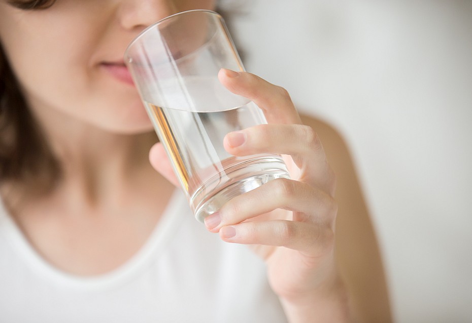 Frau trinkt Wasser vor Blutspende bei Hitze.