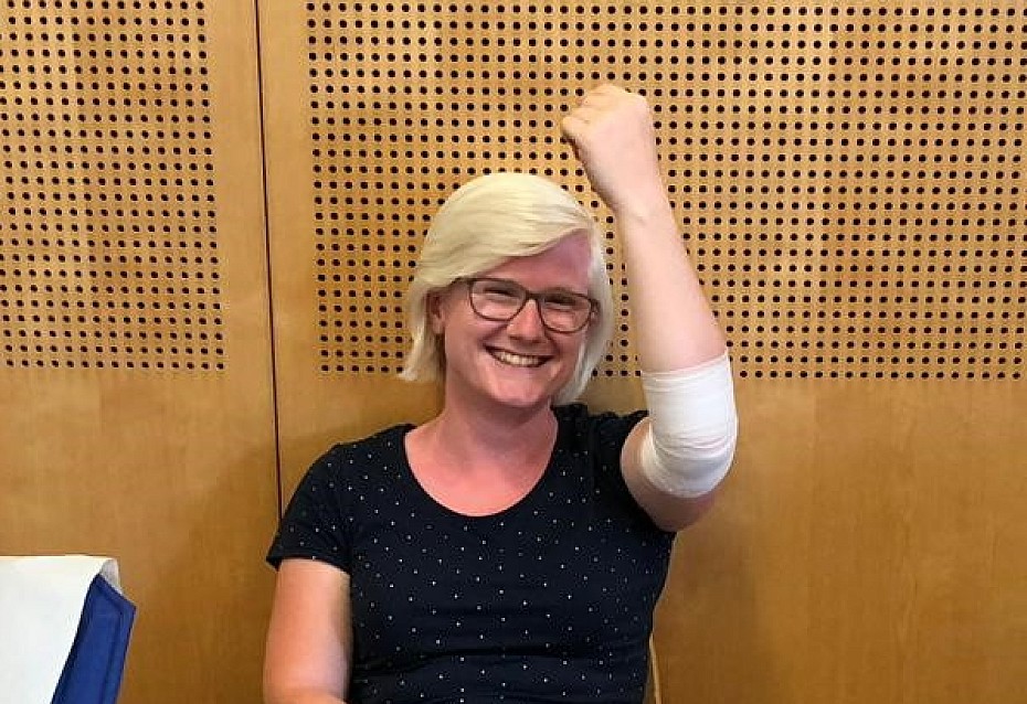 Fiona hält nach der Blutspende fröhlich den verbundenen Arm in die Höhe