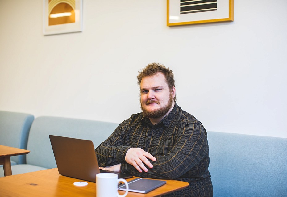 Mann im karierten Hemd mit Laptop im Cafe