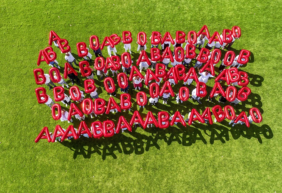 Menschen halte rote Ballonbuchstaben hoch: A, B und 0 – die Symbole für die Blutgruppen