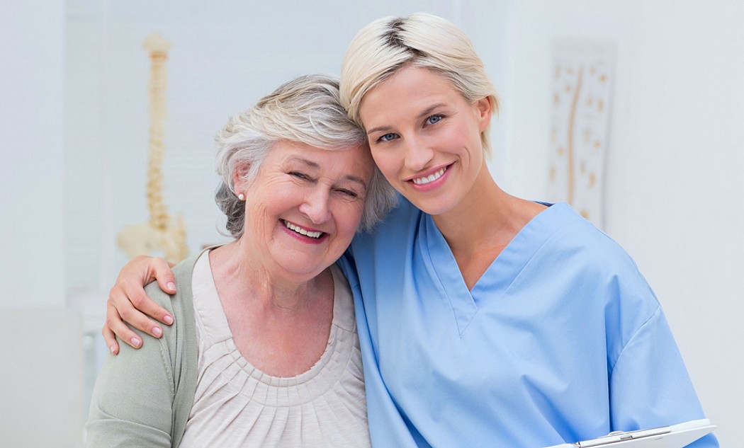 Pflegerin und eine ältere Frau umarmen sich