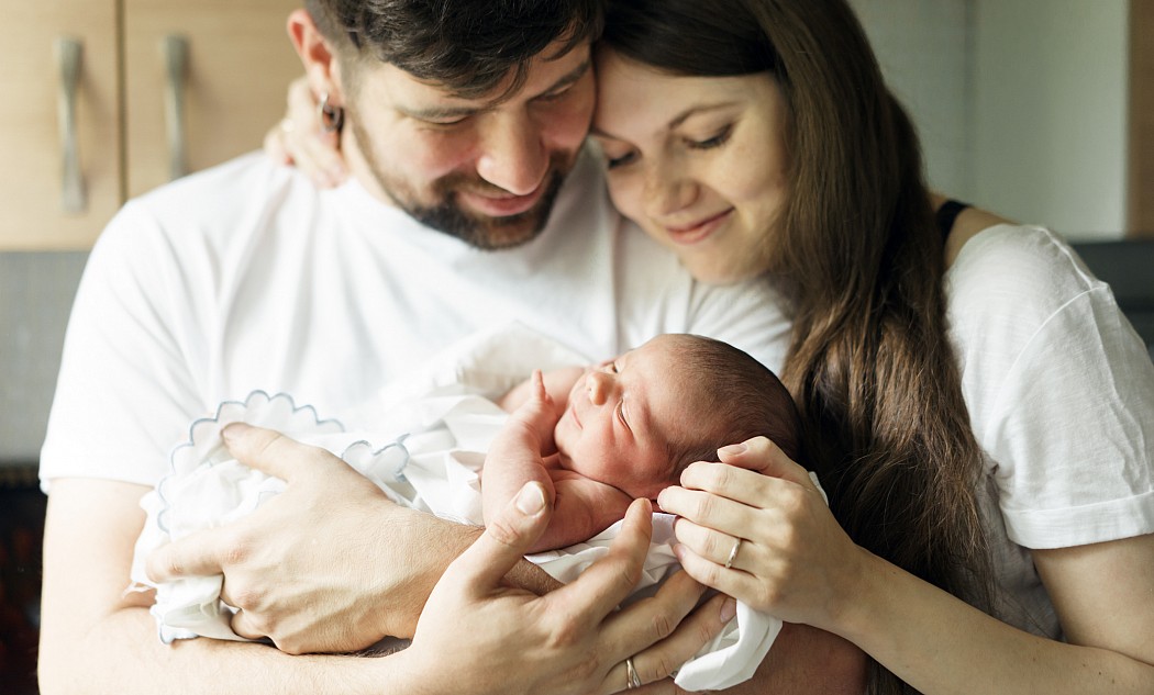 Mutter und Vater halten ihr Neugeborenes im Arm