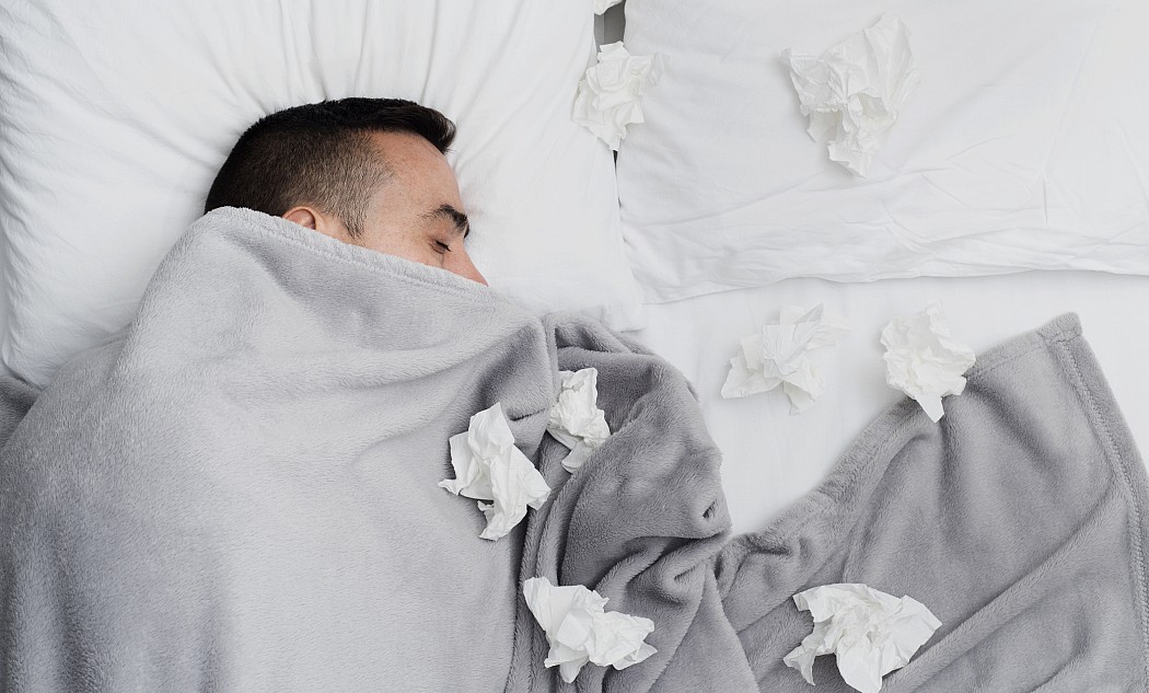 Mann liegt mit einer Grippe krank im Bett
