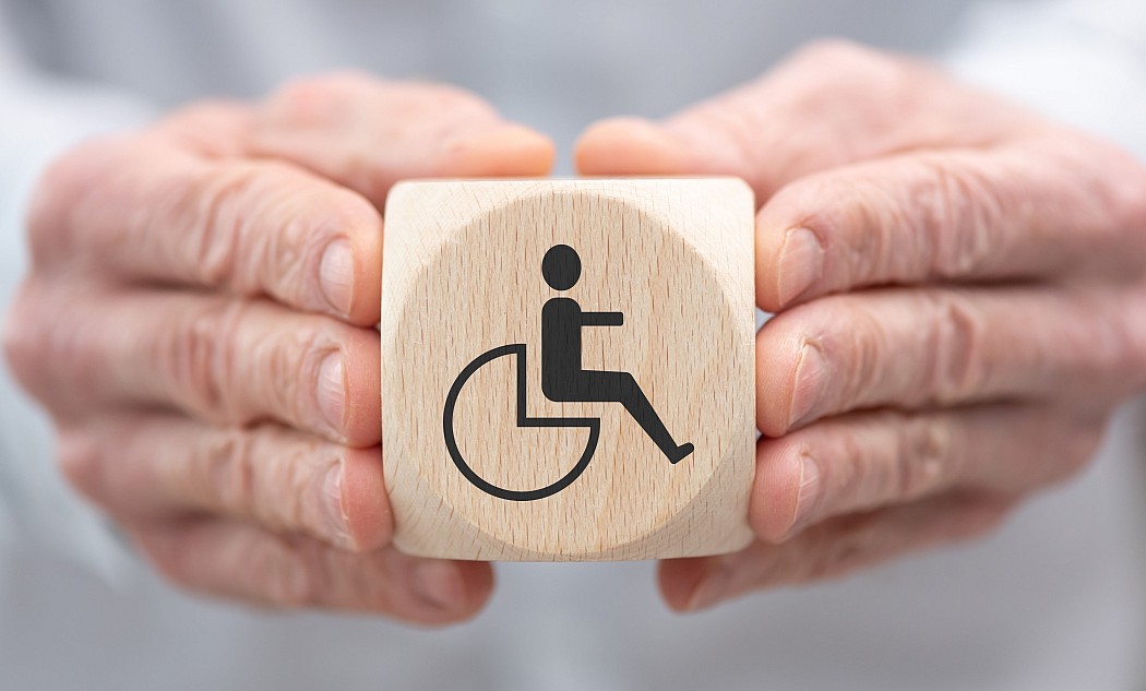hände-halten-holzwürfel-würfel-symbol-behinderung-rollstuhl
