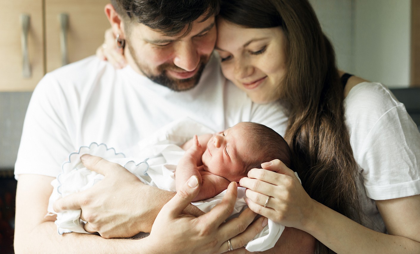 Mutter und Vater halten ihr Neugeborenes im Arm