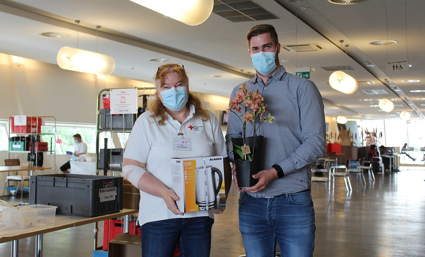 Jan-Cay von Appen vom DRK-Blutspendedienst überreicht Evi Schumacher Blumen und ein Geschenk anlässlich ihrer 100. Spende
