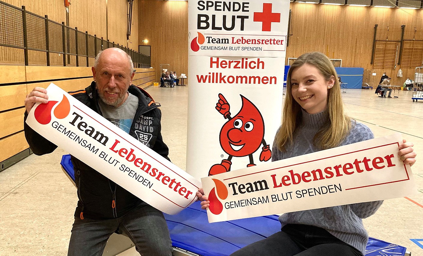 Blutspender sitzen auf Liege halten Plakat Team Lebensretter