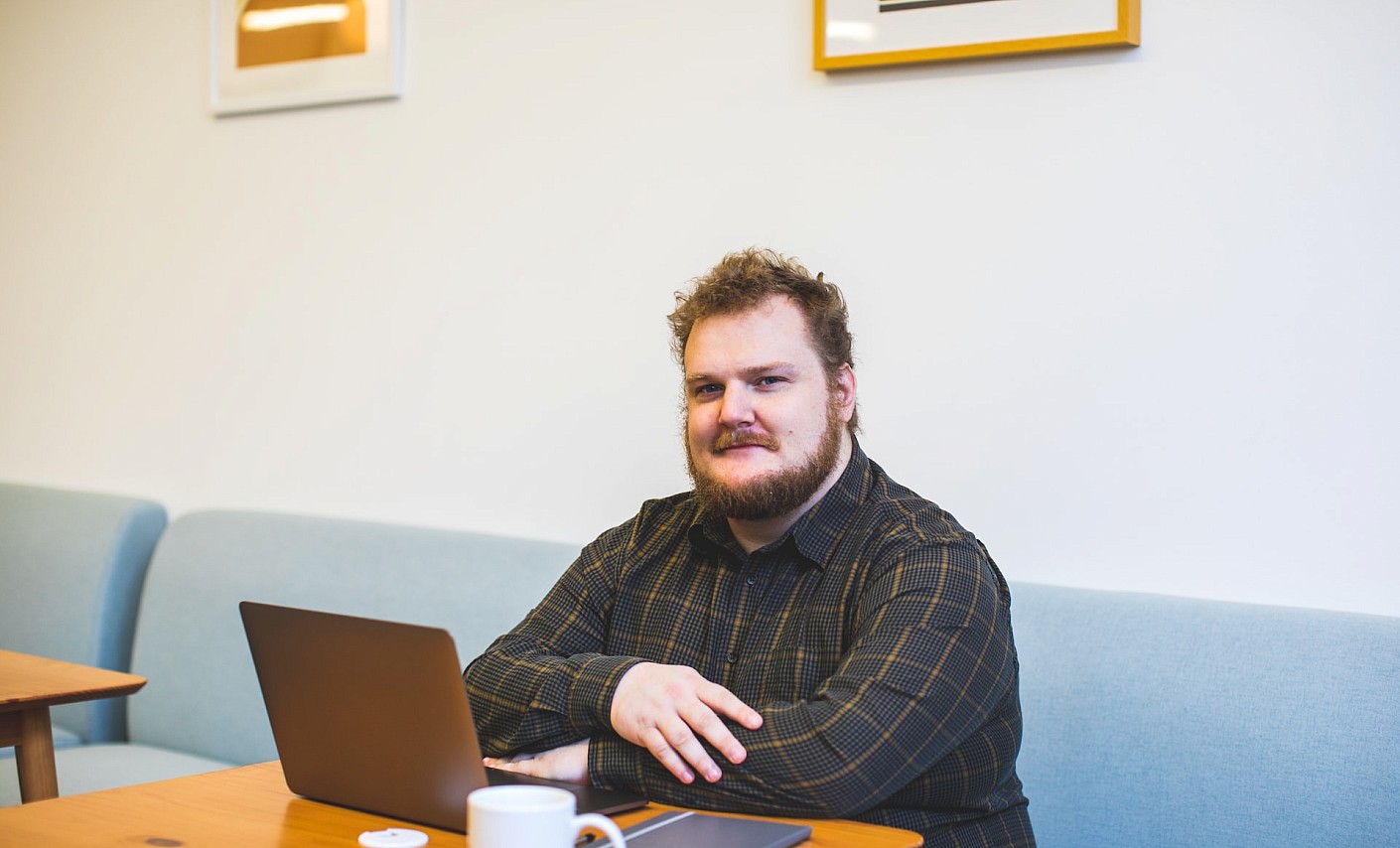 Mann im karierten Hemd mit Laptop im Cafe 