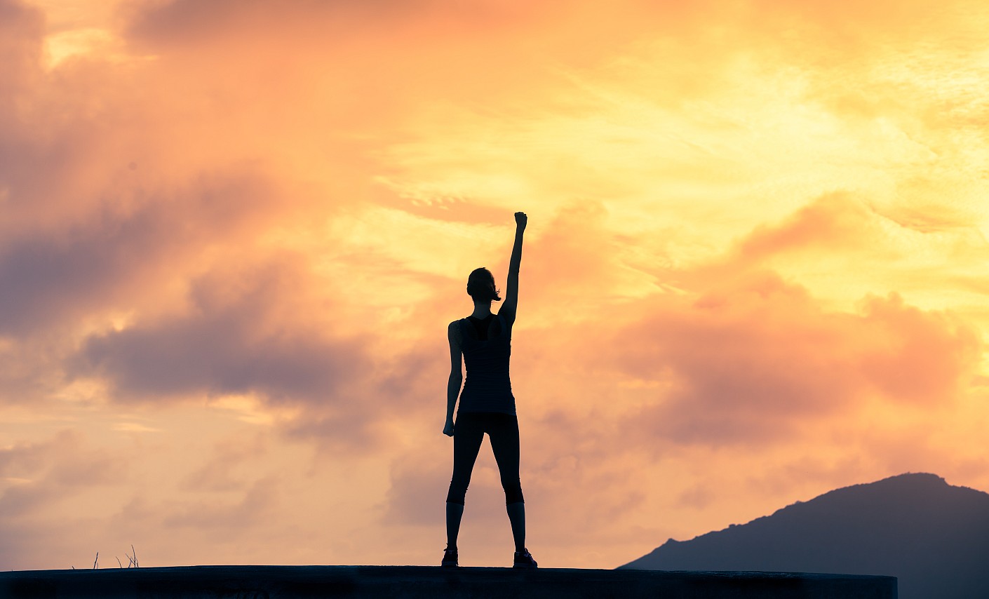 Trau dich! Frau vor Sonnenuntergang hebt die Faust