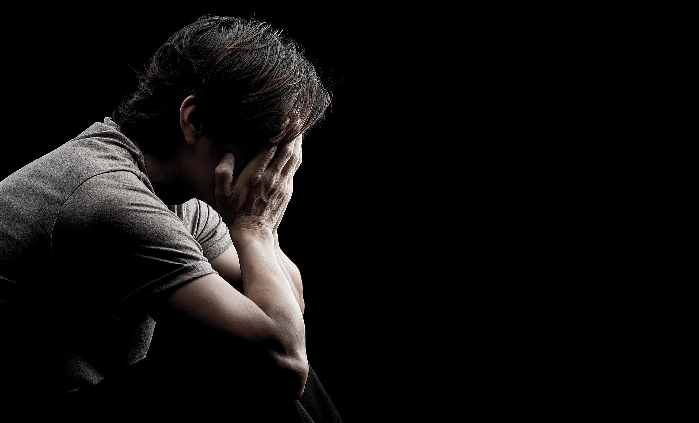 Angst kann belastend sein Mann vor schwarzem Hintergrund hat das Gesicht in den Händen
