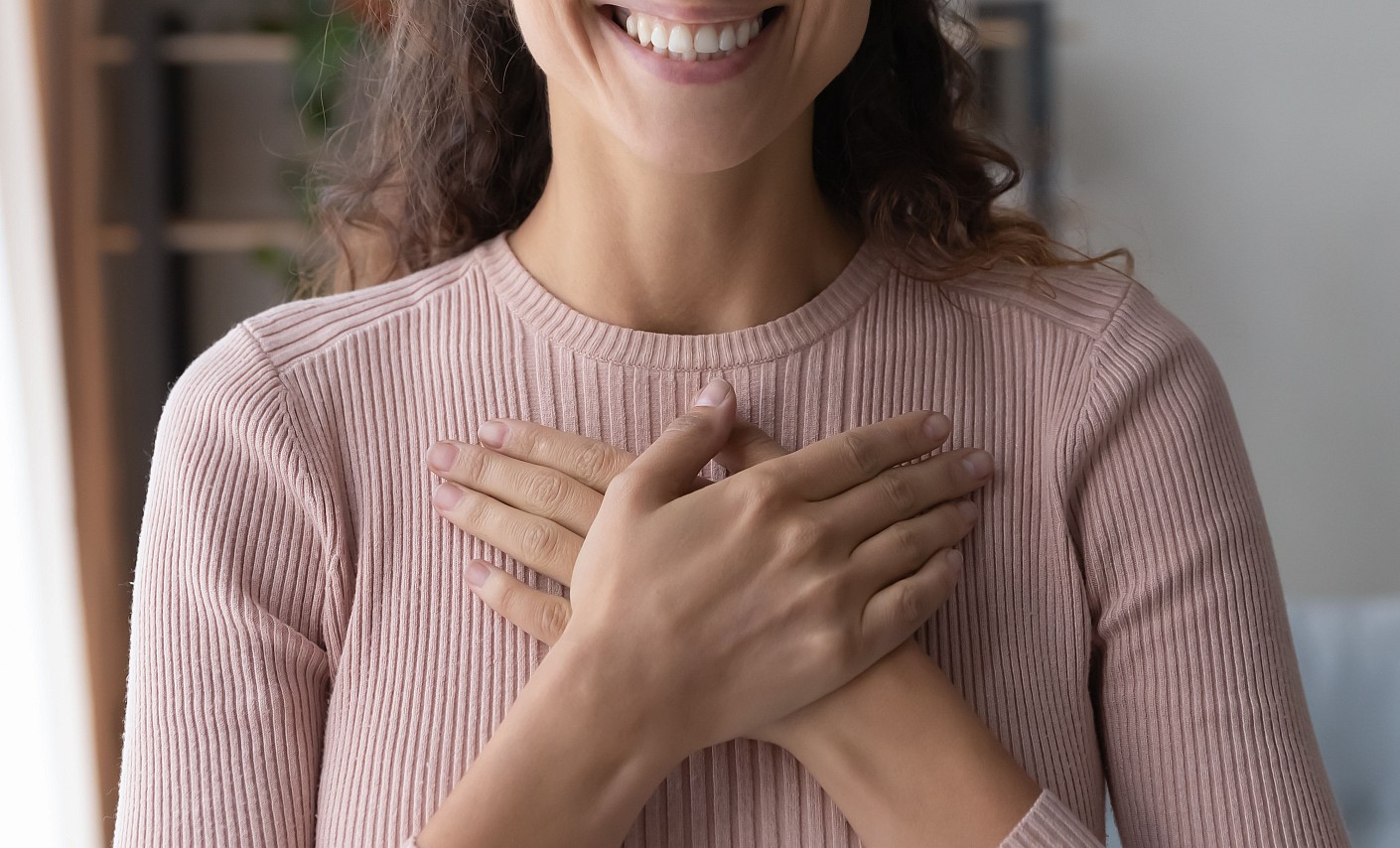 Frau hält ihre Hände in einer dankbaren Geste vor der Brust