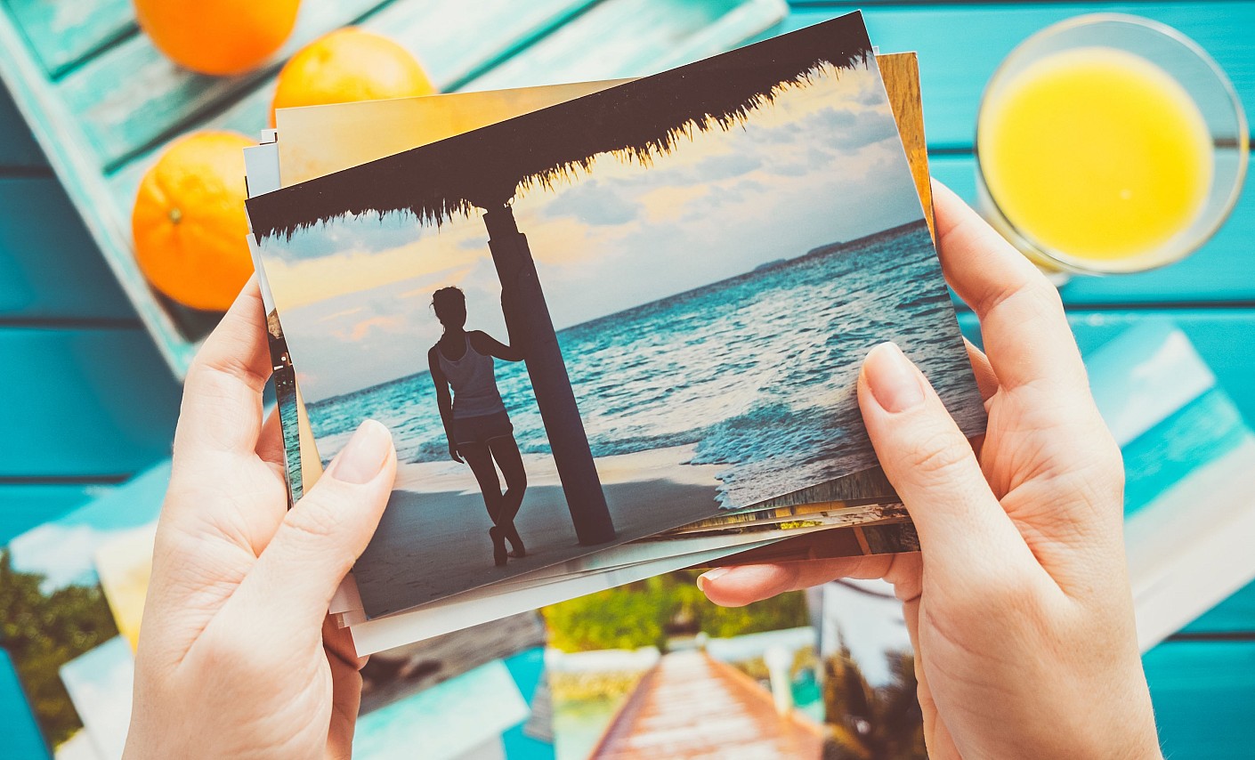 Schöne Erinnerungen sind kleine Ausflüge aus dem Alltag Zwei Hände halten einen Stapel Urlaubsfotos