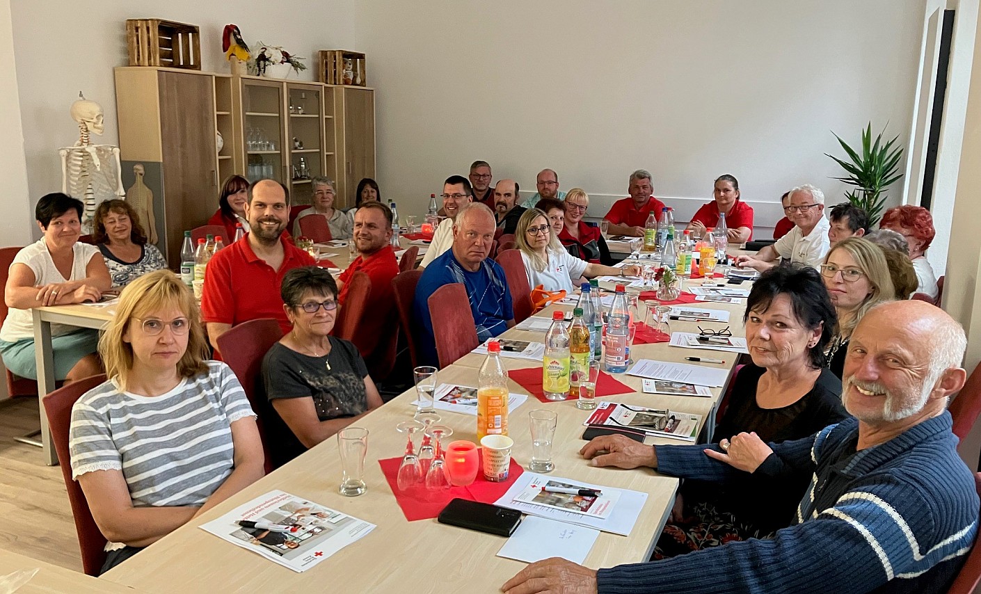 Ehrenamtliche Helferinnen und Helfer sitzen gemeinsam am Tisch im Rahmen der Heferschulung in Lößnitz 