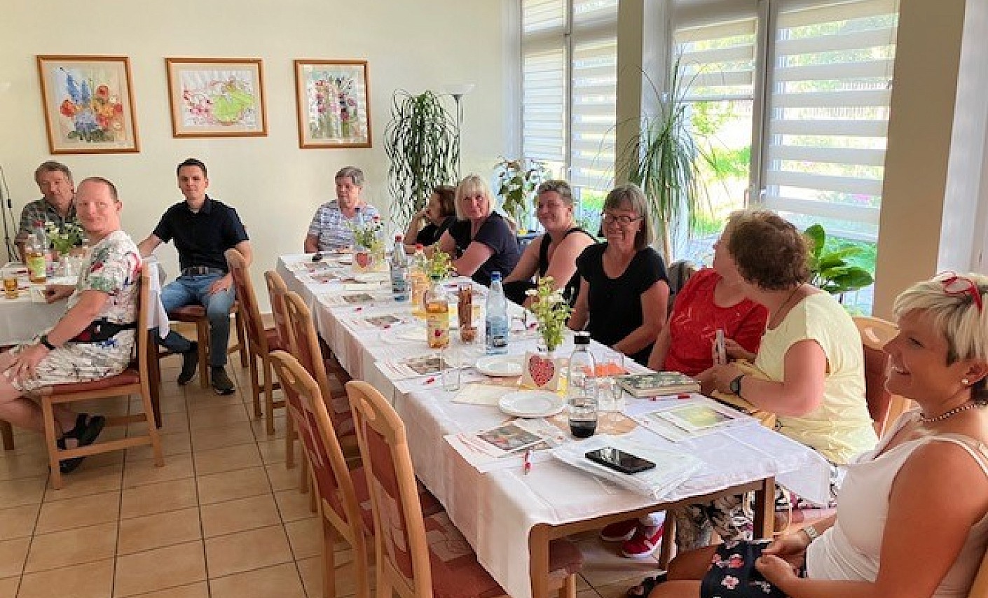 Ehrenamtliche Helferinnen und Helfer sitzen gemeinsam am Tisch im Rahmen der Helferschulung in Zwickau