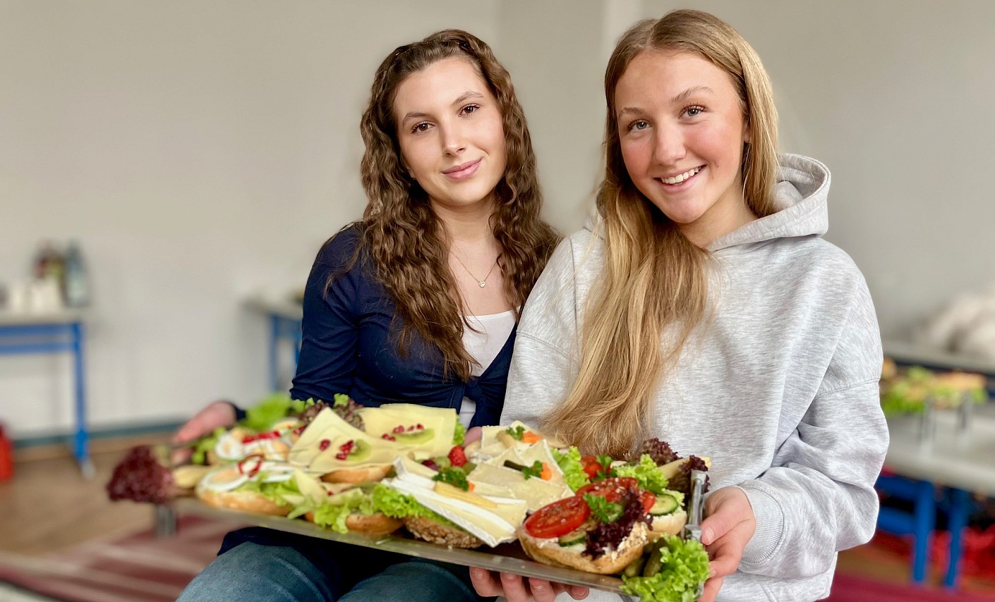 Annabelle und Lenya haben sich selbstständig um die Verpflegung der Blutspender gekümmert zwei-frauen-sitzen-tablett-brötchen-bewirtung-blutspende