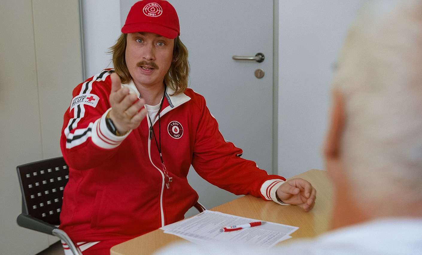 Coach Rob sitzt im Arztzimmer für seinen Spendecheck