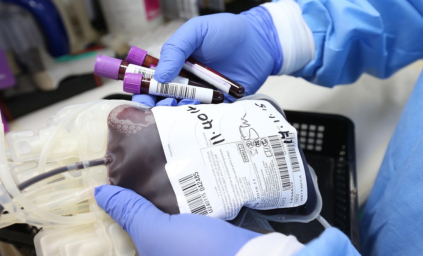 Blutkonserve und Blutröhrchen Medizinisches Personal mit Schutzkleidung hält Blutkonserve und Blutproben in den Händen