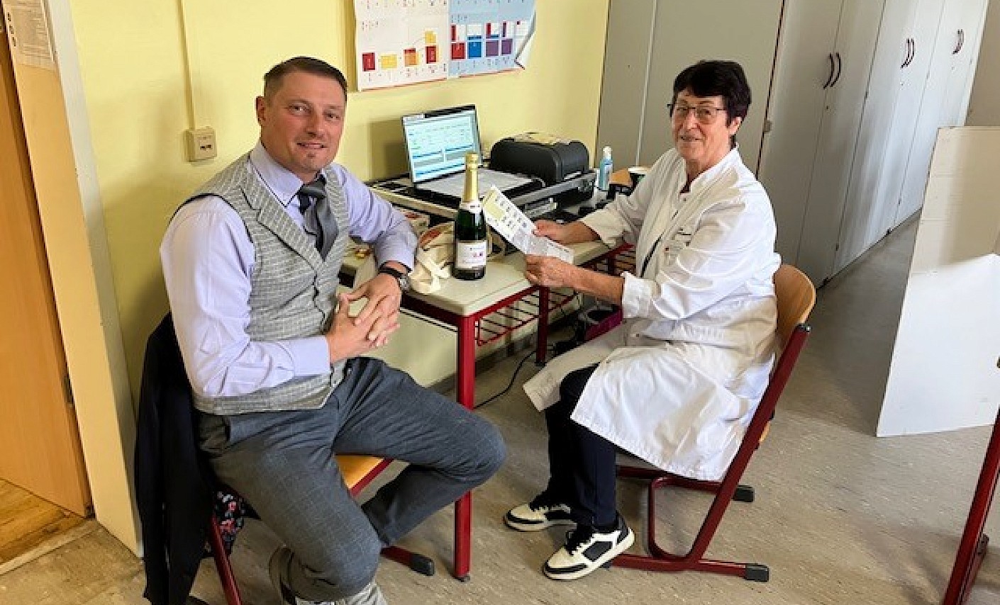 Thomas Lang sitzt mit Dr. Christina Unger beim Anamnesegespräch und erhält seine Auszeichnung  