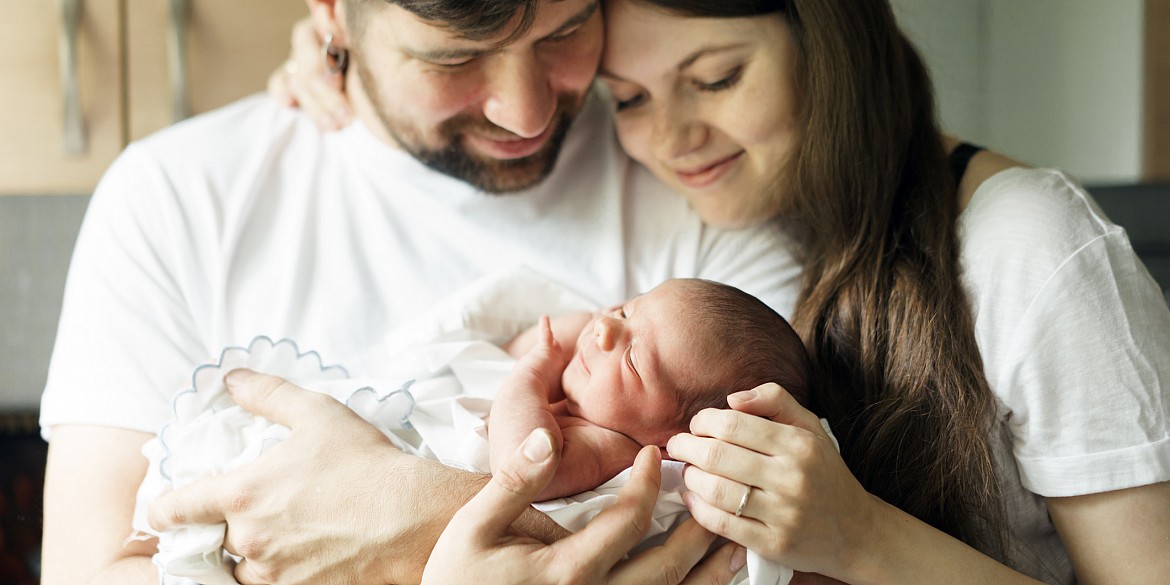 Mutter und Vater halten ihr Neugeborenes im Arm