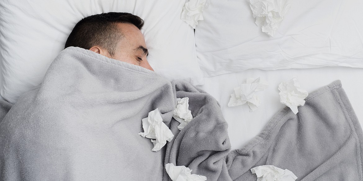 Mann liegt mit einer Grippe krank im Bett