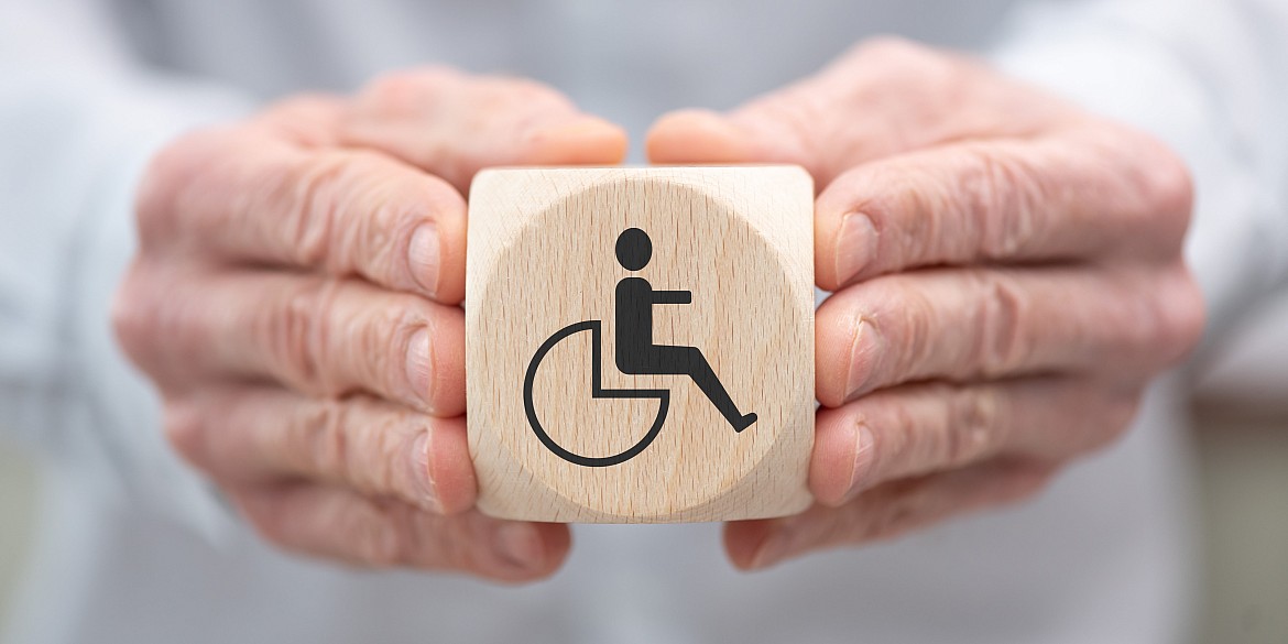 hände-halten-holzwürfel-würfel-symbol-behinderung-rollstuhl