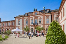 Zeigt das Schloss Biebrich und Personen, die sich dem Eingang nähern