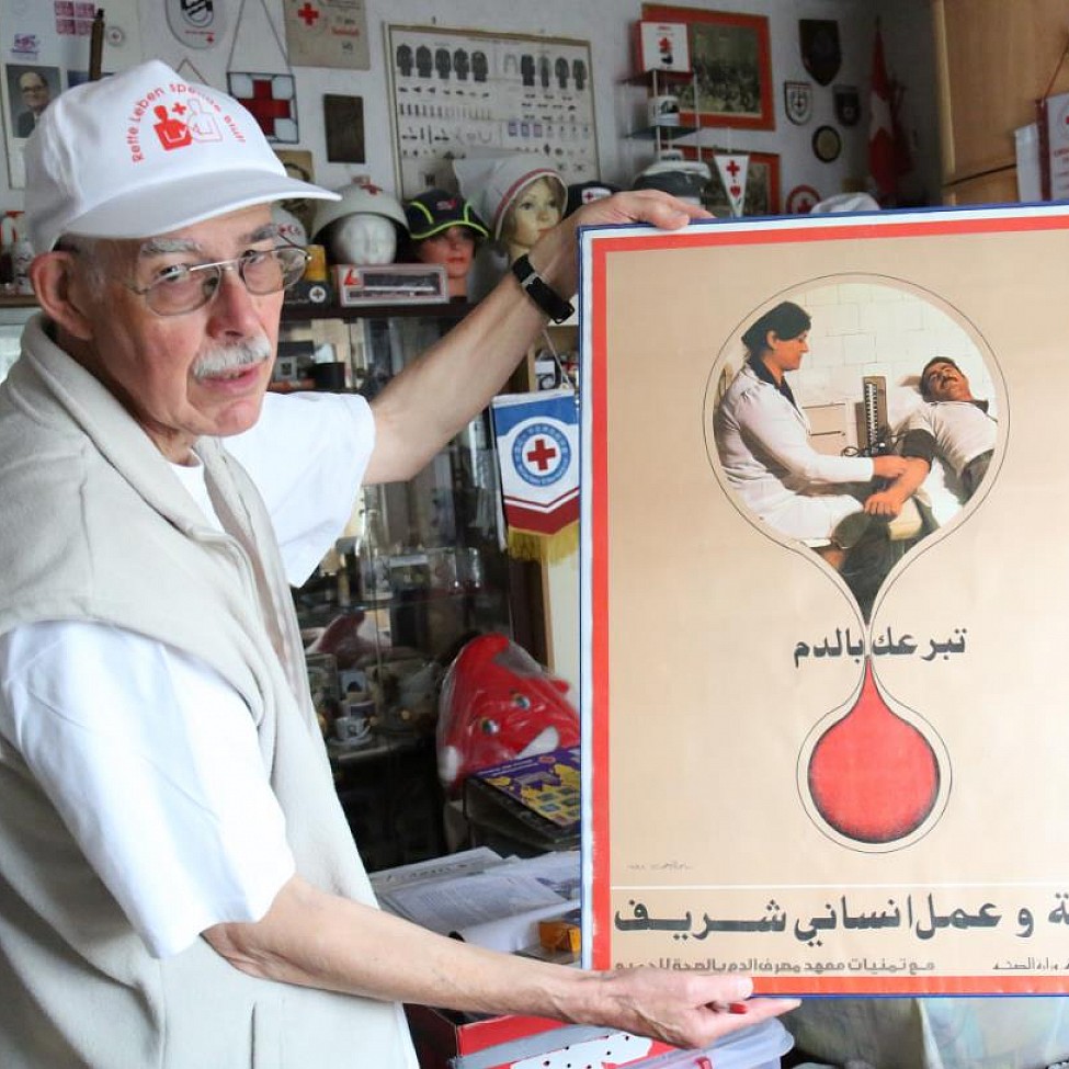 Dietrich Holle mit einem Blutspendeplakat aus dem Irak