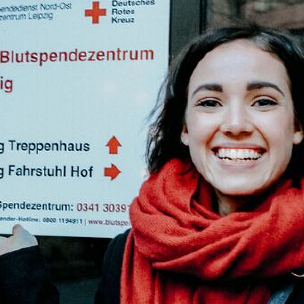 Frau mit Immunthrombozytopenie steht vor dem DRK Blutspendezentrum Leipzig