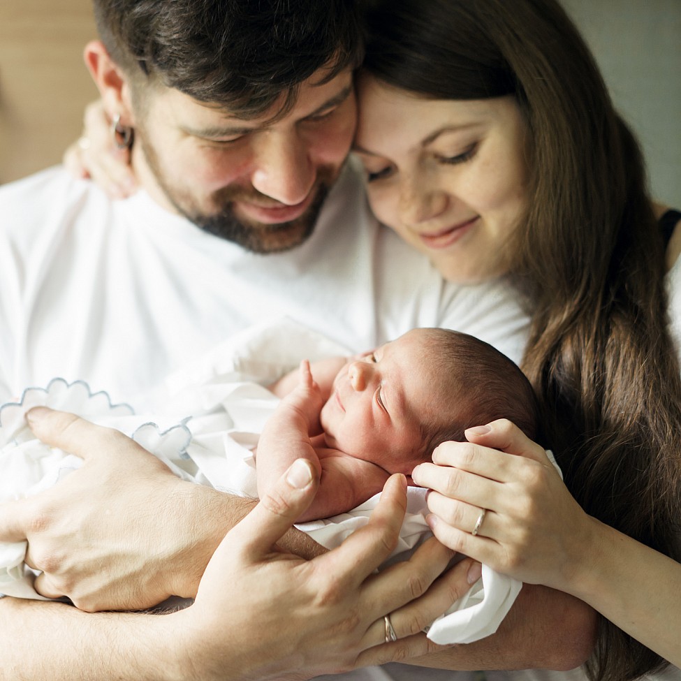 Mutter und Vater halten ihr Neugeborenes im Arm