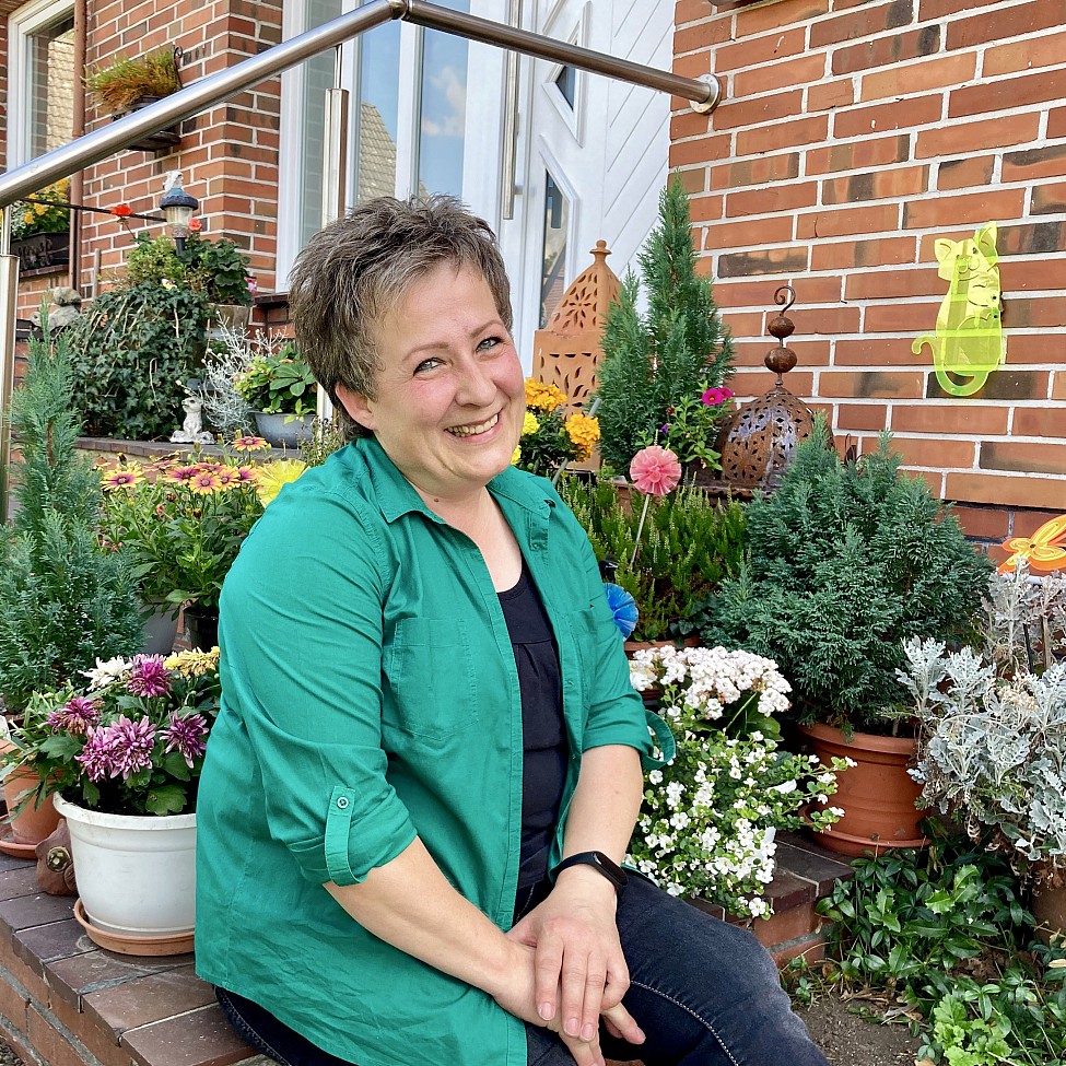 Marion Lammers Gedichtautorin, sitzen vor Haus, lächeln