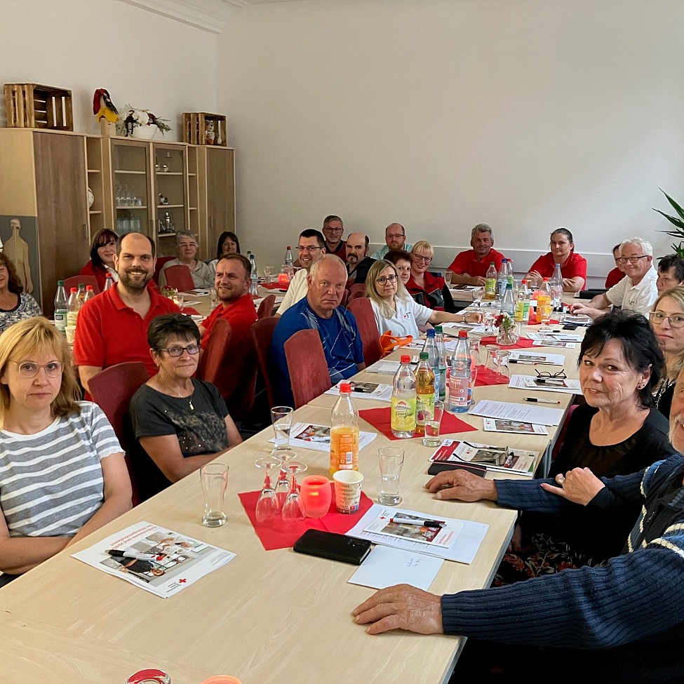 Ehrenamtliche Helferinnen und Helfer sitzen gemeinsam am Tisch im Rahmen der Heferschulung in Lößnitz 